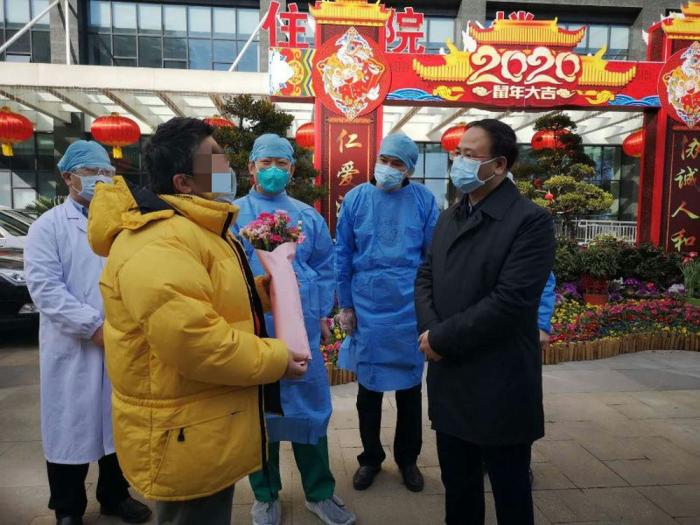图为湖北省台办主任李建红(右一)在武汉协和医院迎接痊愈出院的台胞金先生(黄衣者)。湖北省台办供图