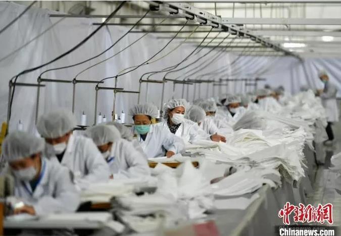 工人们在生产线上有条不紊地生产医用防护服。　翟羽佳 摄