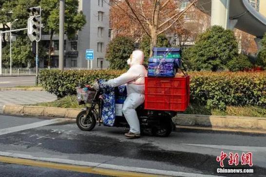 资料图：2月5日，湖北武汉武珞路，一位身穿防护服的配送员在工作中。中新社记者 张畅 摄