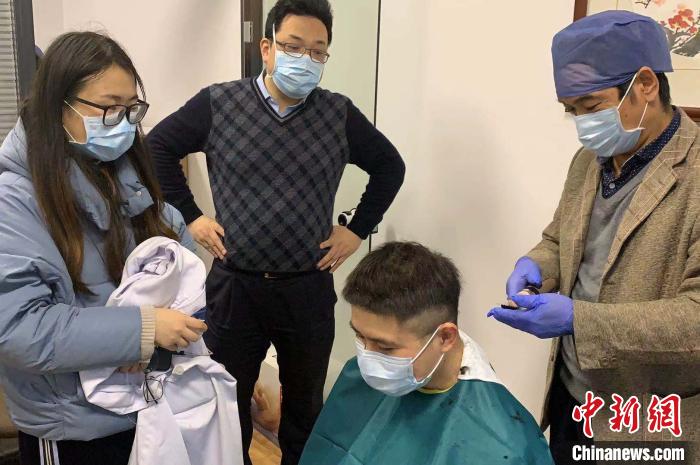 在同事和未婚妻的注视下，陆超再次坐下剪发。　张斌 摄