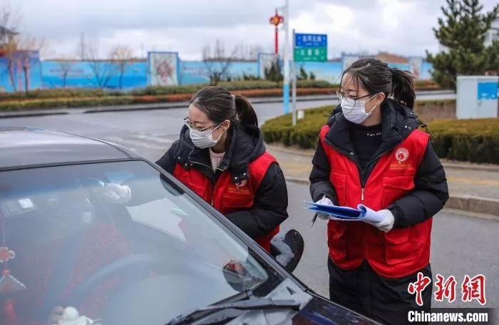 工作人员对居民小区出入口进行设卡体温检测、登记。 李信君 摄