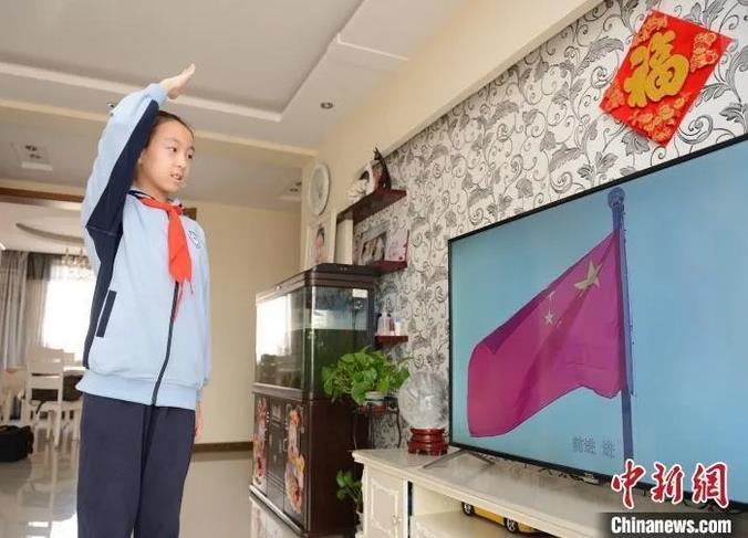 2月29日，一名小学在家中通过视频参加线上升旗仪式。　刘文华 摄